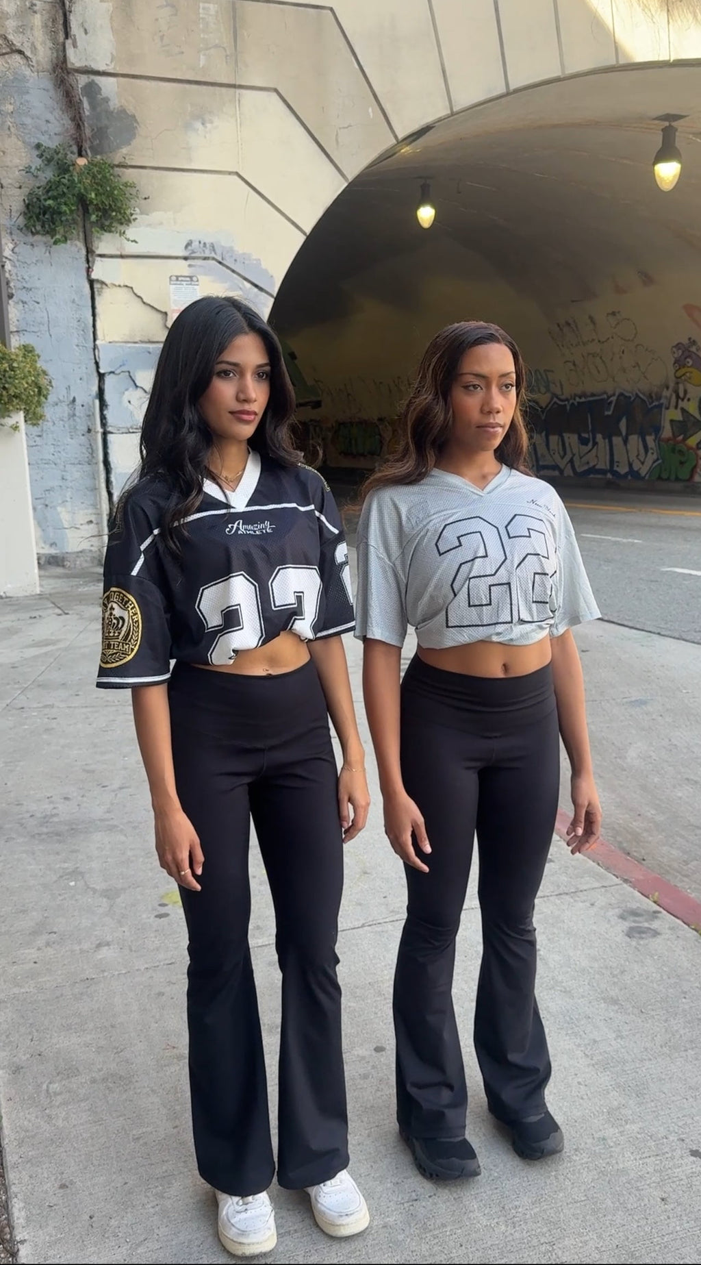 Two women wearing matching outfits with the number 23 in an urban setting.